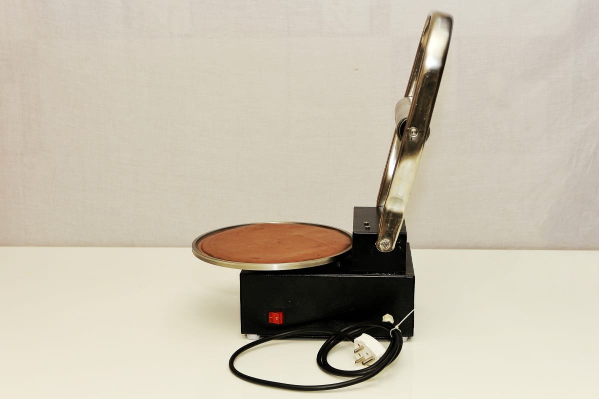 RotiMitra Side View with Lower Plate Side view of the RotiMitra assisted dough-pressing appliance showing the circular lower plate and power cable.